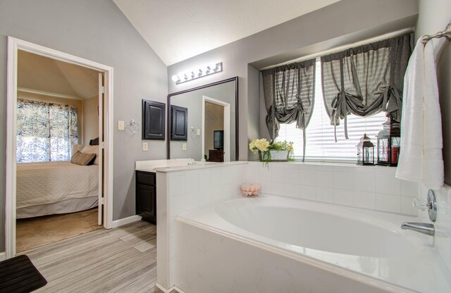 14022 Cypress Falls Dr, Cypress, TX 77429 - full bathroom with vaulted ceiling, connected bathroom, a bath, vanity, and baseboards