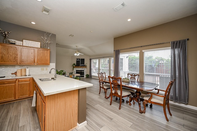 14022 Cypress Falls Dr, Cypress, TX 77429 - kitchen with a sink, ceiling fan, a fireplace, tasteful backsplash, and light wood finished floors
