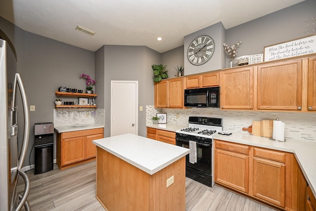 14022 Cypress Falls Dr, Cypress, TX 77429 - kitchen with black microwave, range with gas cooktop, freestanding refrigerator, decorative backsplash, and a kitchen island