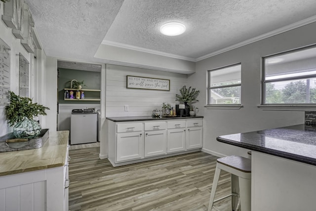 1985 Eastridge Ln, Madisonville, TX 77864 - bar with a textured ceiling, baseboards, ornamental molding, washer and dryer, and light wood-type flooring
