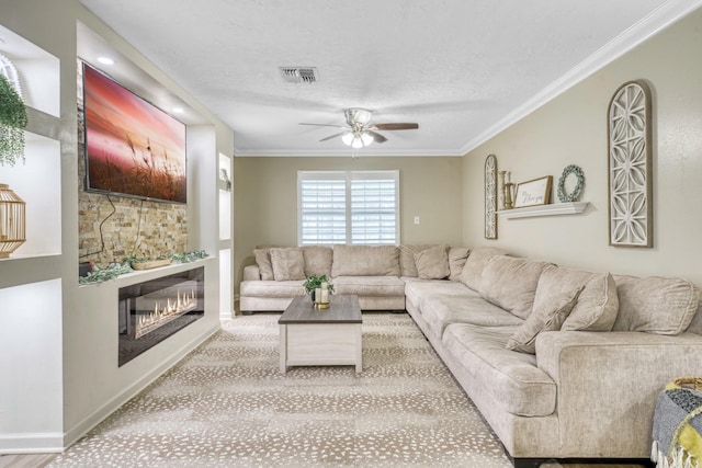 1985 Eastridge Ln, Madisonville, TX 77864 - living room with a textured ceiling, ornamental molding, a glass covered fireplace, visible vents, and ceiling fan
