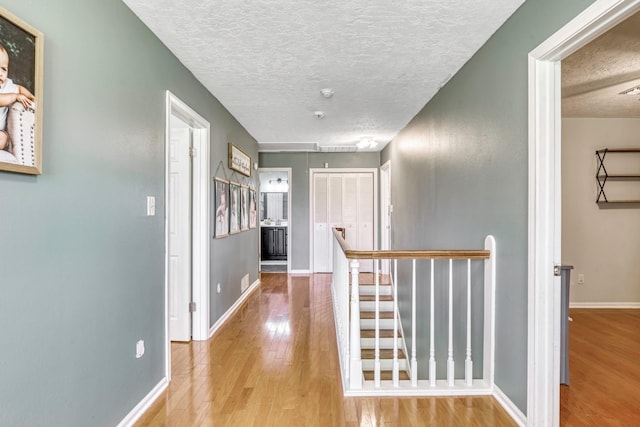 1985 Eastridge Ln, Madisonville, TX 77864 - hall with wood finished floors, an upstairs landing, attic access, a textured ceiling, and baseboards