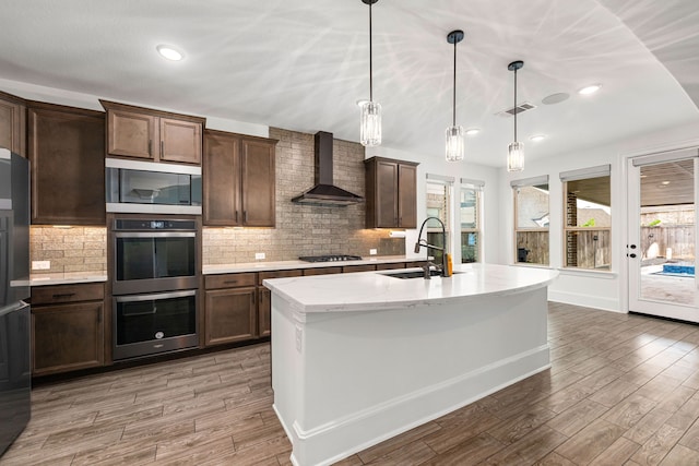 16202 Coyote Run Ln, Cypress, TX 77433 - kitchen featuring wall chimney range hood, stainless steel appliances, light wood-type flooring, tasteful backsplash, and recessed lighting