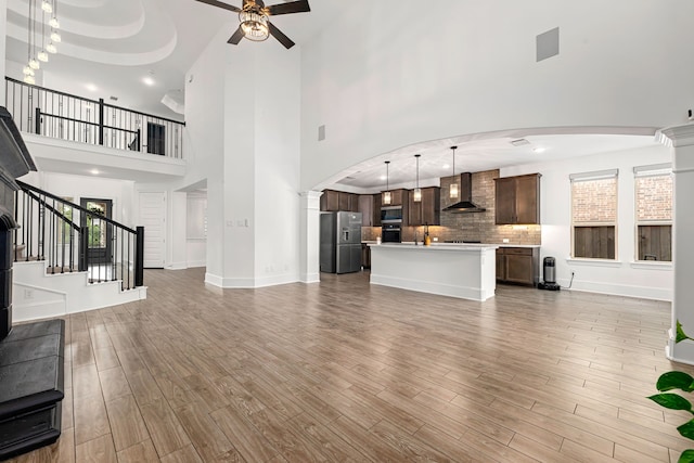 16202 Coyote Run Ln, Cypress, TX 77433 - unfurnished living room featuring a high ceiling, ceiling fan, light wood-style floors, arched walkways, and stairs