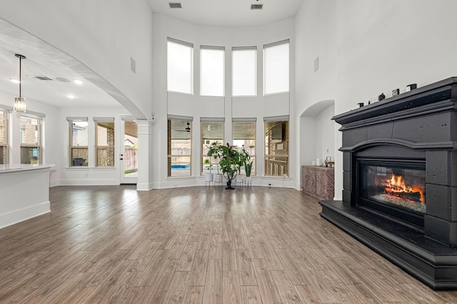 16202 Coyote Run Ln, Cypress, TX 77433 - unfurnished living room with arched walkways, a glass covered fireplace, a high ceiling, and wood finished floors