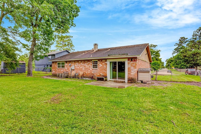 rear view of house featuring a yard, a patio, brick siding, and fence