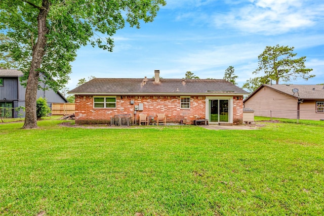 rear view of house with a yard, a patio area, fence, and brick siding