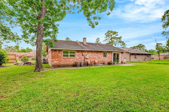 rear view of house with fence, a patio area, brick siding, a lawn, and a shingled roof