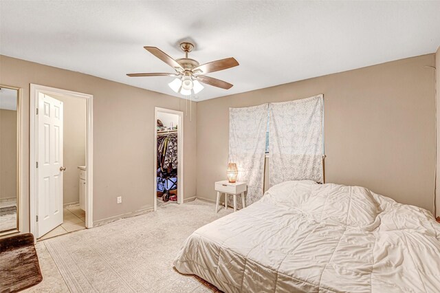 bedroom featuring light tile patterned floors, a ceiling fan, a closet, ensuite bath, and a spacious closet