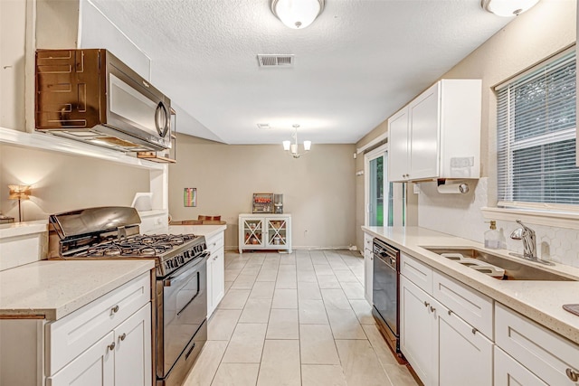 kitchen featuring stainless steel range with gas cooktop, a sink, a textured ceiling, dishwasher, and white cabinets