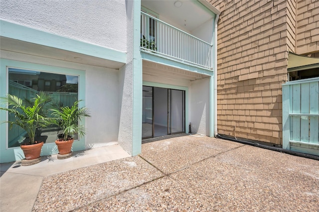 exterior space with stucco siding, a patio area, and a balcony