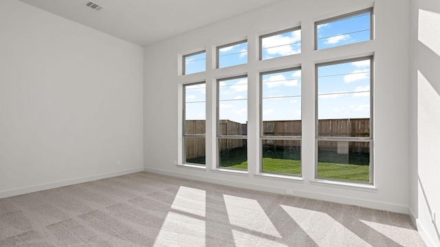 empty room featuring baseboards, light carpet, and visible vents