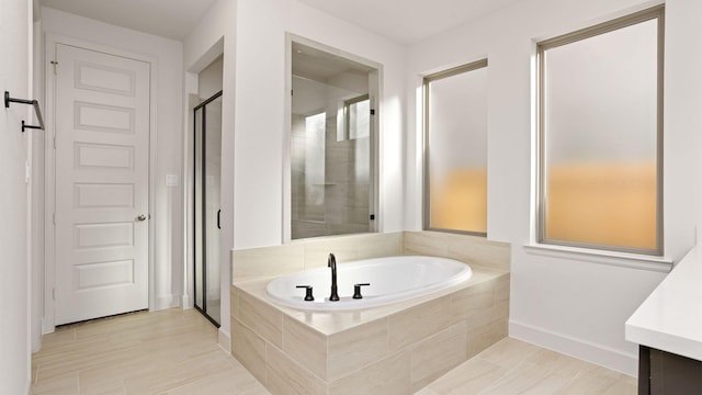 bathroom featuring a stall shower, baseboards, vanity, and a bath