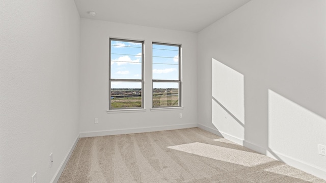 spare room featuring baseboards and light colored carpet