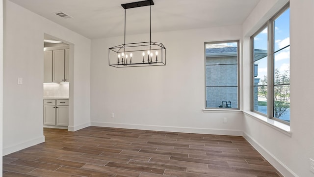unfurnished dining area featuring dark wood-style flooring, baseboards, and visible vents