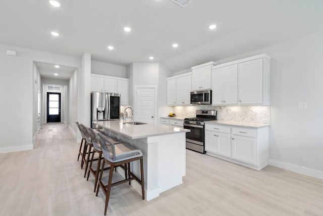 444 Texoma Plains Dr, Conroe, TX 77304 - kitchen featuring a sink, an island with sink, backsplash, a kitchen bar, and appliances with stainless steel finishes