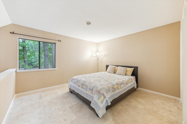bedroom with lofted ceiling, baseboards, and light colored carpet