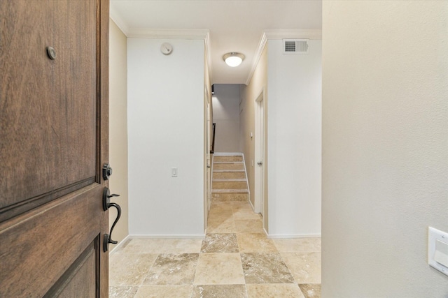 corridor featuring baseboards, ornamental molding, light stone finish flooring, and stairs