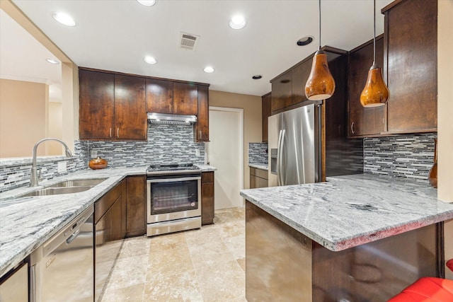 kitchen featuring appliances with stainless steel finishes, a sink, light stone counters, under cabinet range hood, and a peninsula