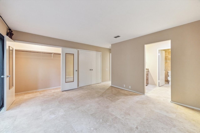 unfurnished bedroom with multiple closets and connected bathroom