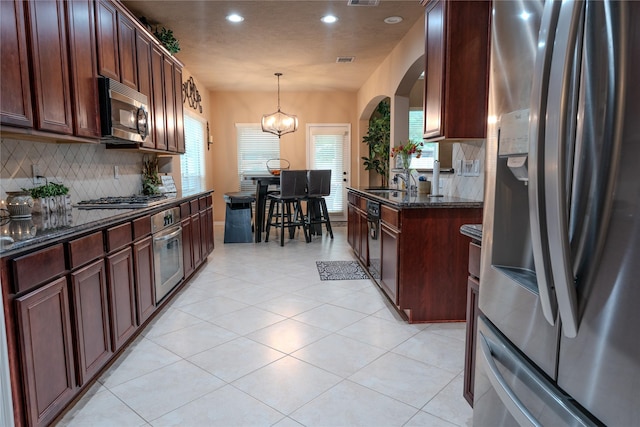 3519 Maverly Crest Ct, Katy, TX 77494 - kitchen featuring stainless steel appliances, decorative backsplash, recessed lighting, arched walkways, and dark stone countertops