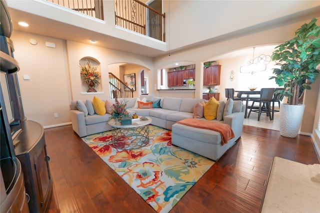 3519 Maverly Crest Ct, Katy, TX 77494 - living room with arched walkways, dark wood-style flooring, baseboards, a chandelier, and a high ceiling