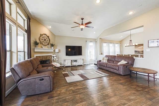 living area featuring vaulted ceiling, a high end fireplace, ceiling fan with notable chandelier, and hardwood / wood-style flooring