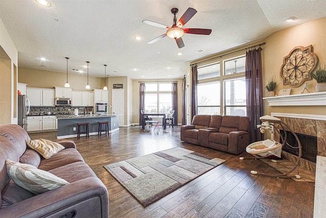 living room with a ceiling fan, dark wood finished floors, a premium fireplace, and recessed lighting