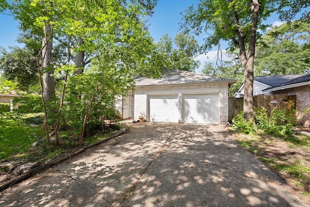 garage with concrete driveway and fence