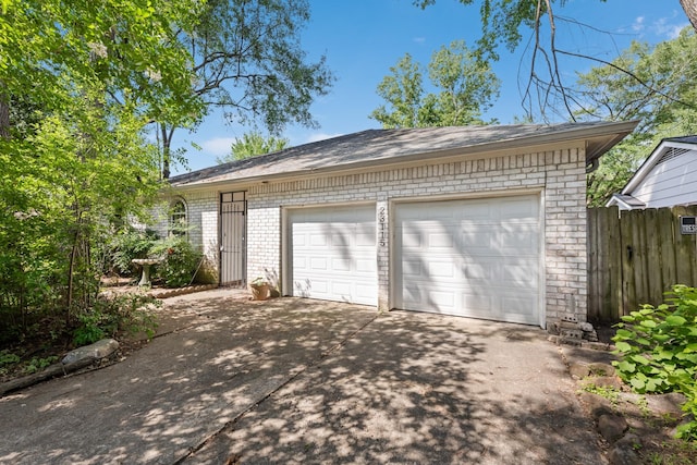 garage featuring driveway and fence