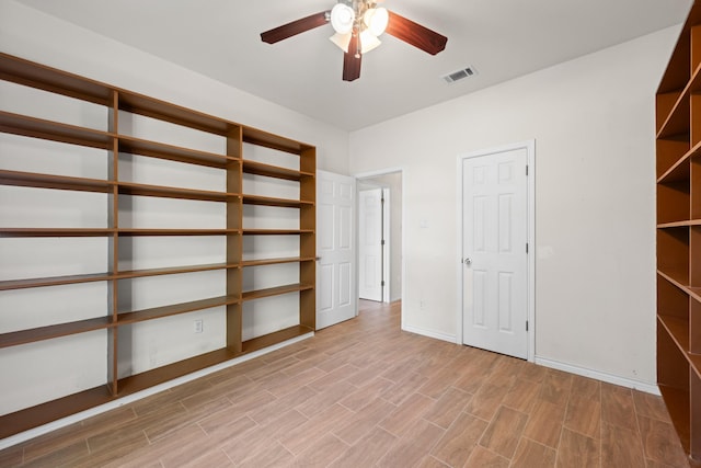 interior space featuring baseboards, visible vents, light wood-type flooring, and ceiling fan