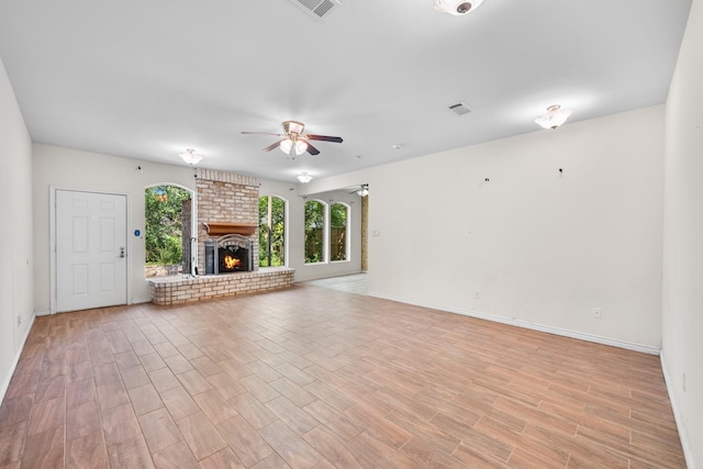 unfurnished living room featuring visible vents, a fireplace, ceiling fan, light wood-style flooring, and baseboards