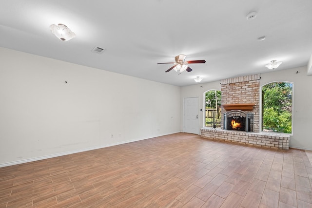 unfurnished living room featuring baseboards, light wood-style flooring, a ceiling fan, and a brick fireplace