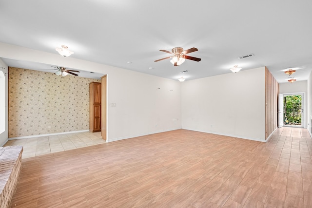 unfurnished living room with light wood-style floors, visible vents, baseboards, and ceiling fan