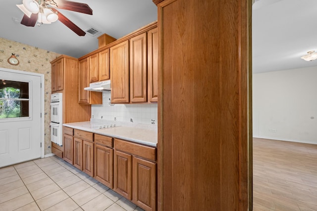 kitchen featuring a ceiling fan, visible vents, white appliances, under cabinet range hood, and light countertops