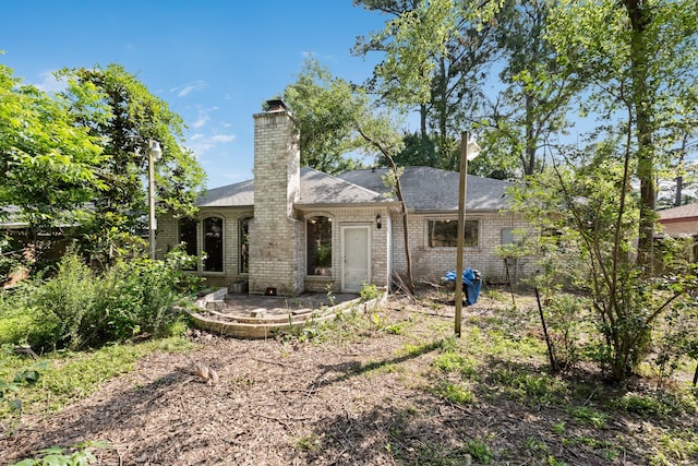 back of house featuring a chimney, a patio, and brick siding