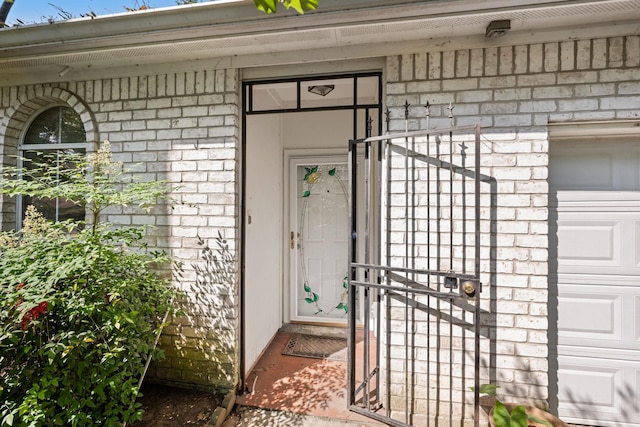 doorway to property featuring stone siding, a garage, and brick siding