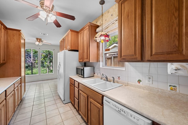 kitchen featuring light tile patterned floors, a ceiling fan, a sink, brown cabinetry, and white appliances