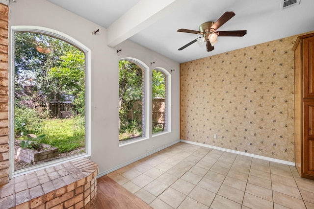 empty room with light tile patterned flooring, a ceiling fan, visible vents, and beam ceiling