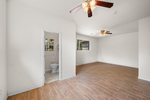 unfurnished bedroom featuring baseboards, connected bathroom, a ceiling fan, and wood finished floors