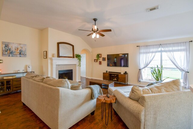 living area featuring lofted ceiling, visible vents, dark wood finished floors, a fireplace, and a ceiling fan