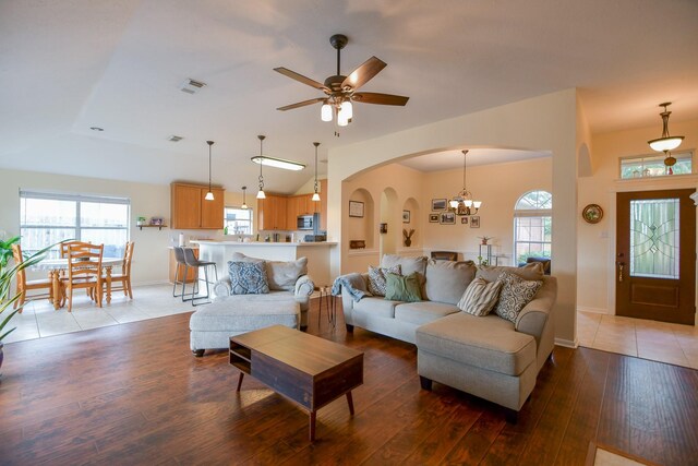 living area featuring ceiling fan with notable chandelier, arched walkways, light wood-type flooring, and a healthy amount of sunlight