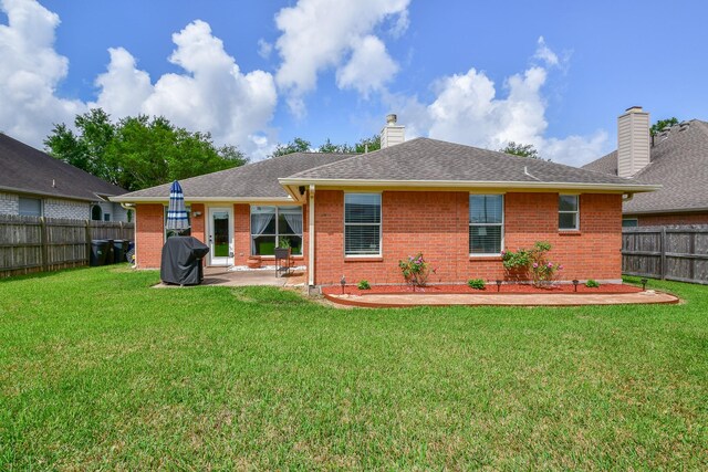rear view of property with brick siding, a patio area, a chimney, and roof with shingles