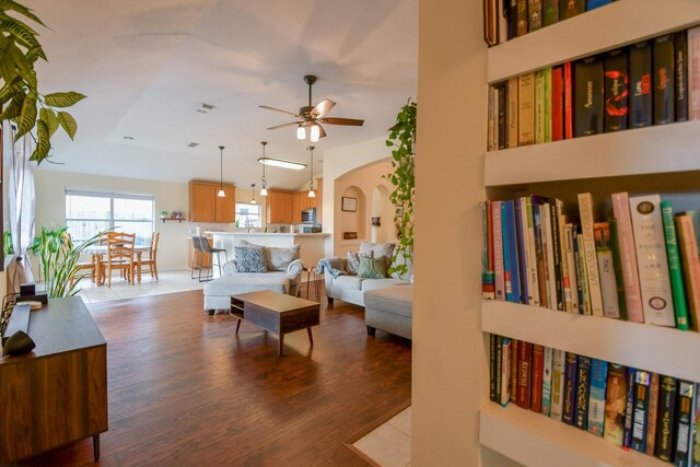 living area with a ceiling fan, arched walkways, wood finished floors, and lofted ceiling