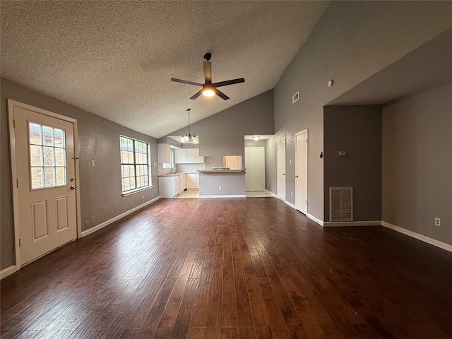 unfurnished living room featuring lofted ceiling, ceiling fan with notable chandelier, a textured ceiling, visible vents, and dark wood finished floors