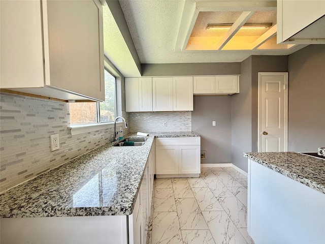 8715 Belle Glen Dr, Houston, TX 77099 - kitchen with a sink, light marble finish flooring, decorative backsplash, white cabinets, and light stone counters