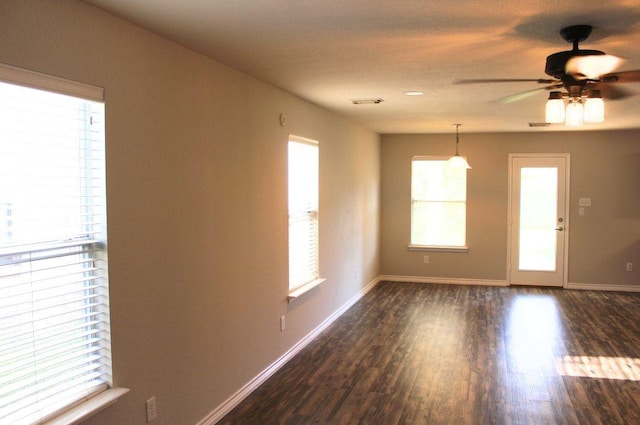 spare room featuring plenty of natural light, dark wood-type flooring, and baseboards