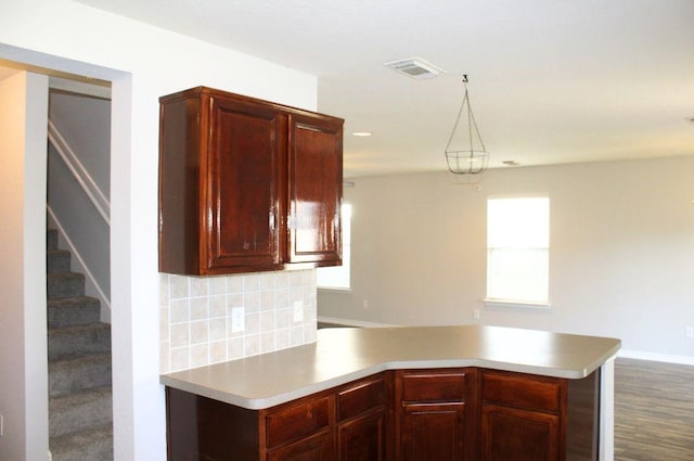 kitchen with a peninsula, decorative backsplash, light countertops, dark wood-style flooring, and baseboards