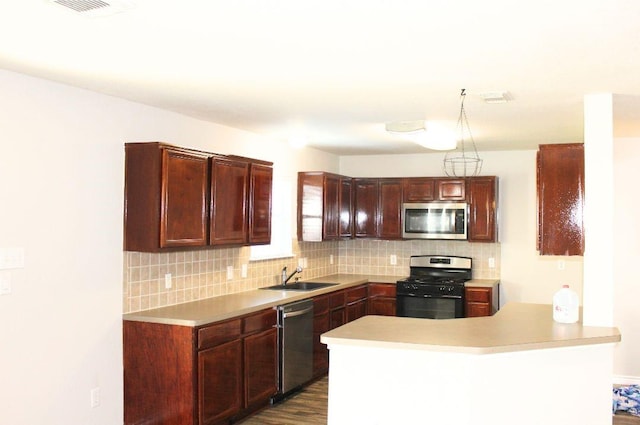 kitchen with stainless steel appliances, a sink, light countertops, decorative backsplash, and a peninsula