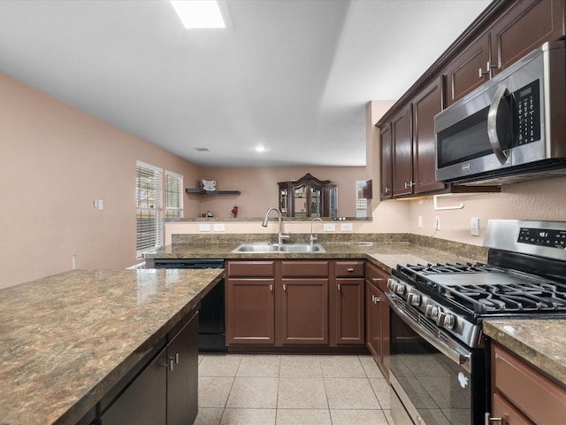 7914 Cypress Edge Dr, Cypress, TX 77433 - kitchen featuring appliances with stainless steel finishes, a sink, a peninsula, light tile patterned flooring, and dark stone counters